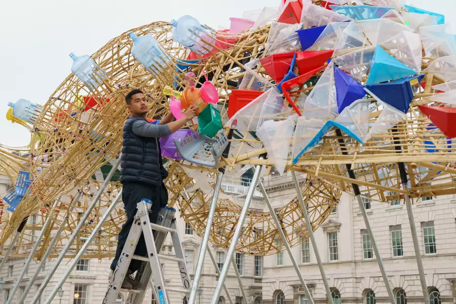 Photo of Leeroy New on a ladder working on his sculpture