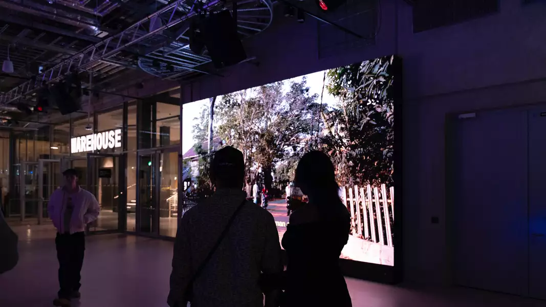Two people stood watching a film on a giant screen at Aviva Studios