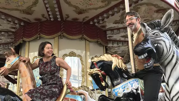 Two people sat on a ferris wheel smiling