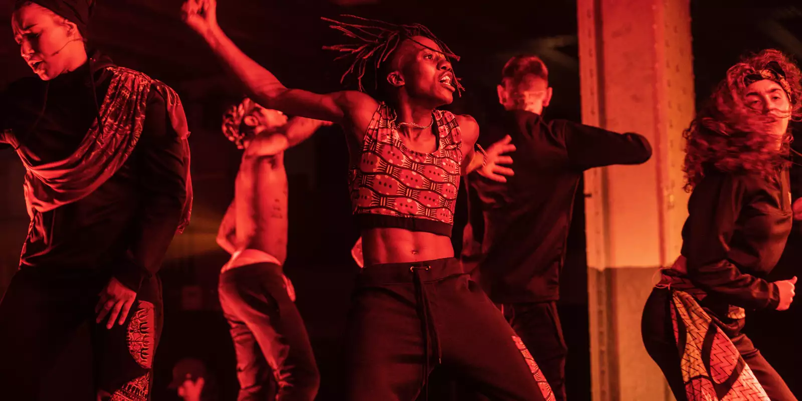 Dancers performing on stage. The image has a red hue.