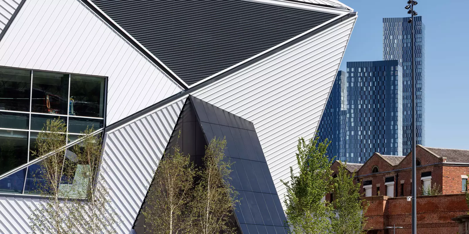 The side of Aviva Studios on a sunny day, with the skyscrapers behind