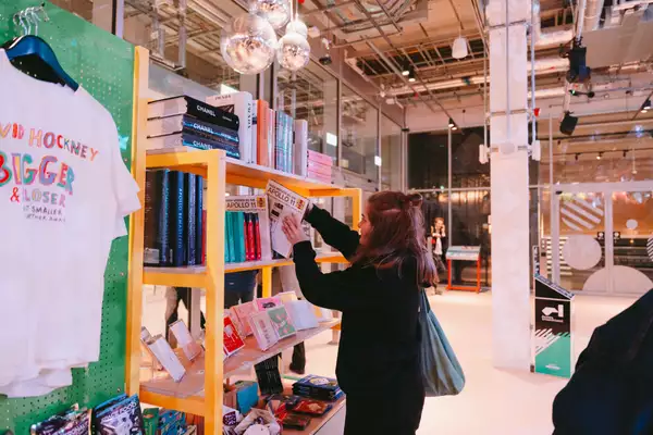 A person looking through some books in the shop at Aviva Studios with glitter balls above their head