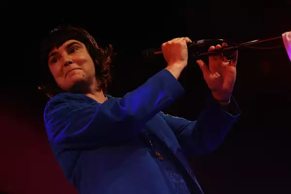 Sinéad O’Connor wearing a dark blue jacket singing into a microphone