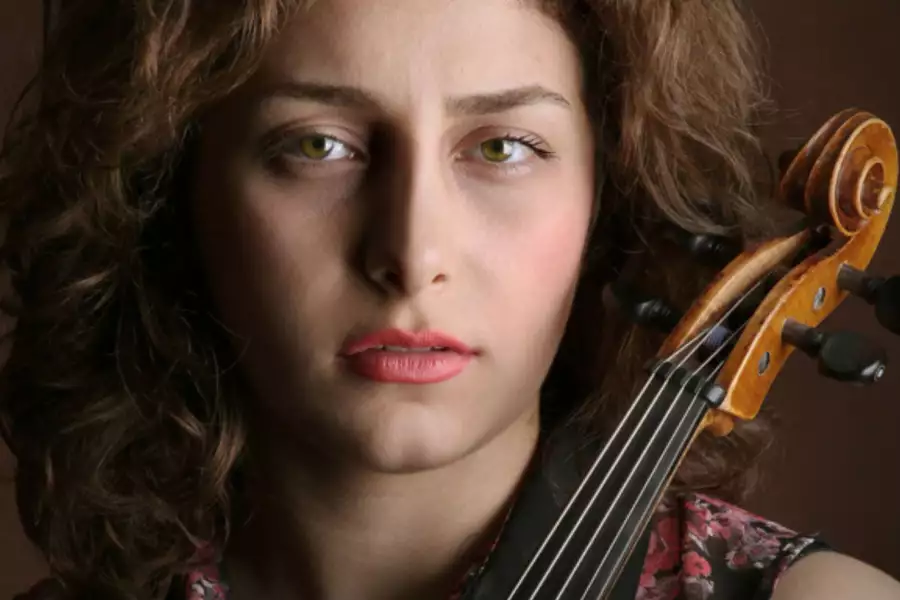 parisa prizadeh looking to camera holding a violin