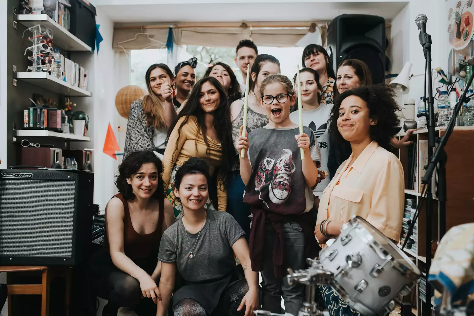 Group photo of young people inside a bedroom with audio equipment and instruments