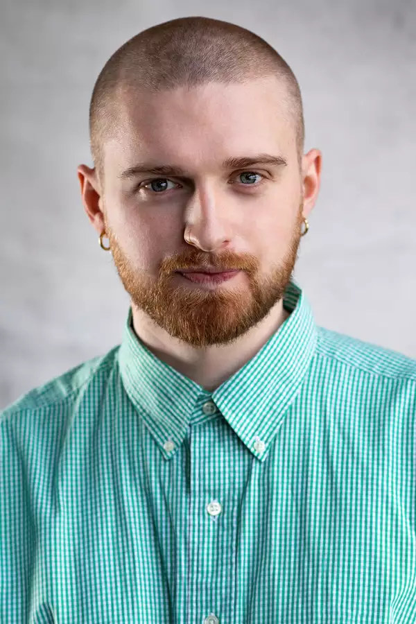 Ronan Cullen in a green gingham shirt with a hoop earring in each ear