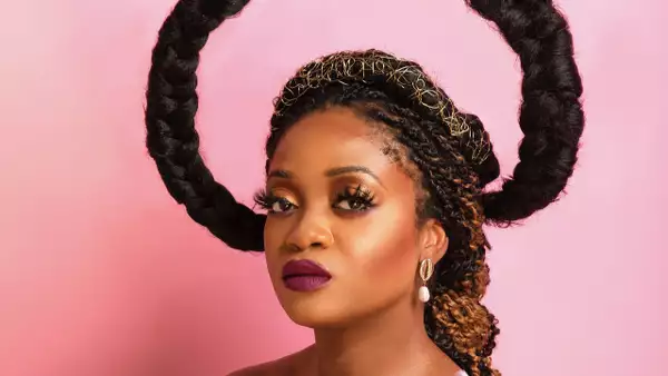 Hazel Mak with their hair styled on a pink background