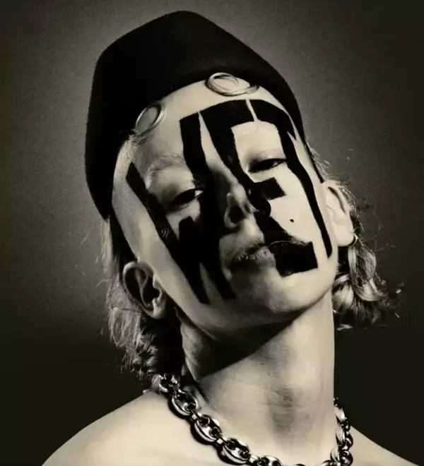 A black and white photograph of the artist Wet Mess with WET written on their face in black kohl