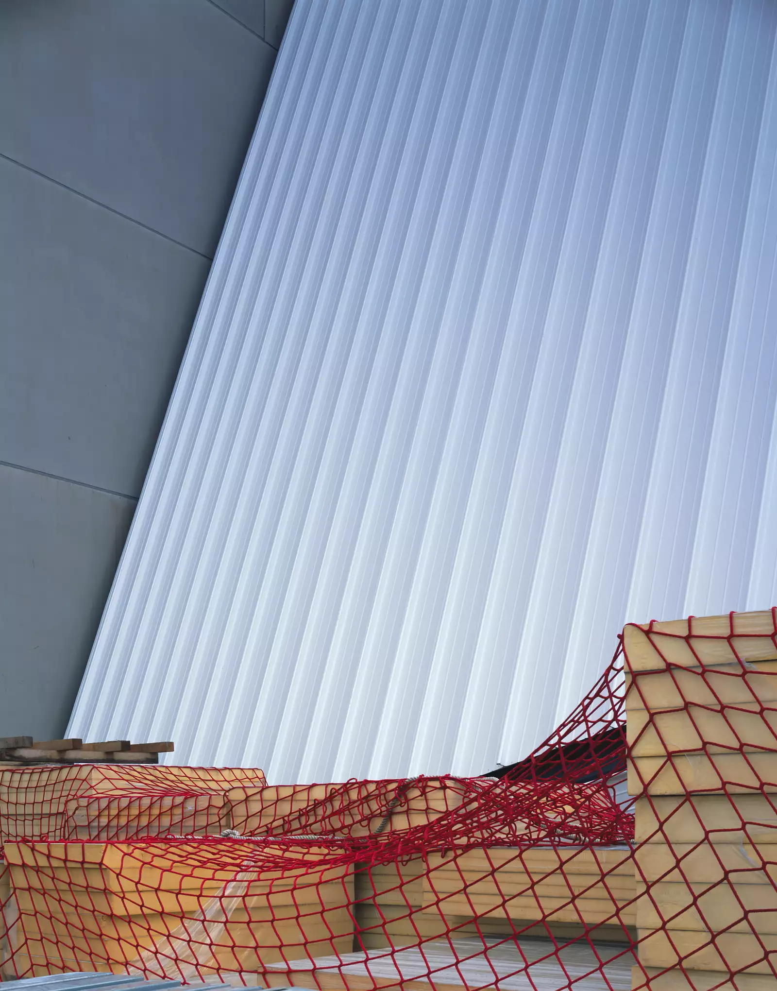 Photograph by Hélène Binet showing the white outside wall of Aviva Studios with red netting on the floor