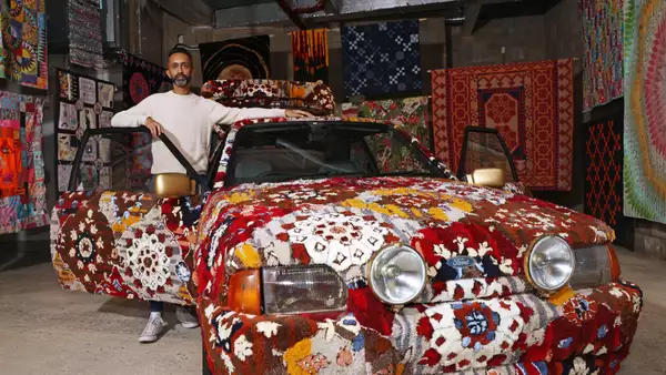 Hetain Patel stood by an artwork, which is a brightly patterned car