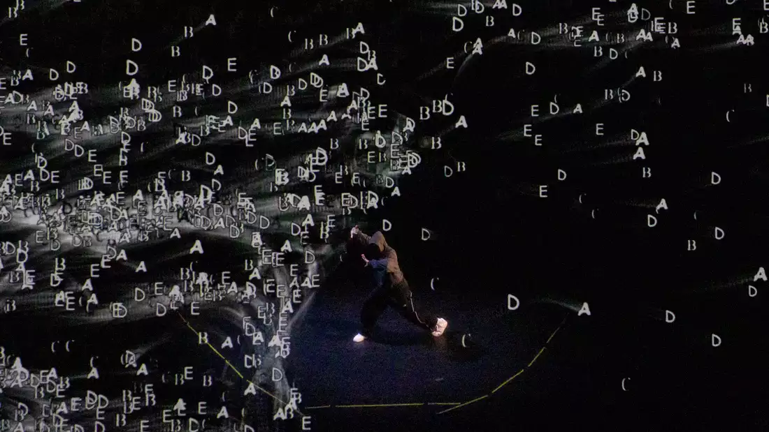 Chad Taylor dancing on stage with lettering on a screen behind him
