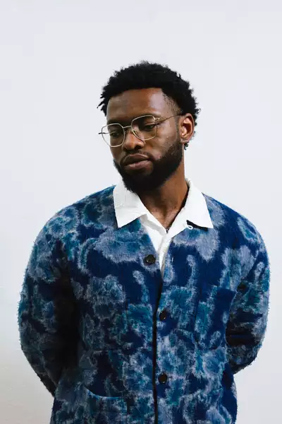 Daniel Oyegade wearing a patterned blue cardigan