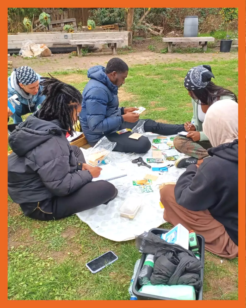 Photo of a group of people sitting on the grass in a garden