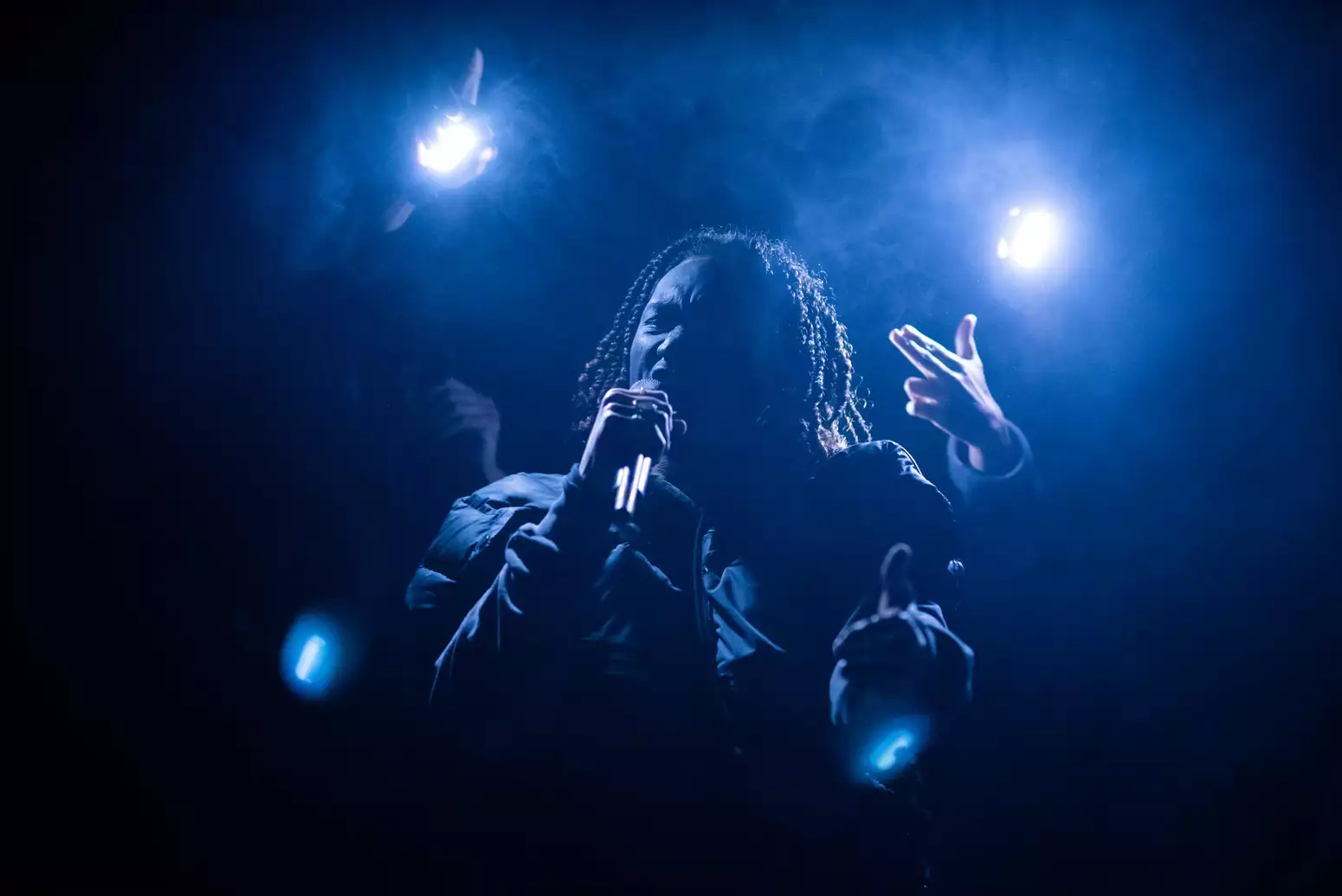 An actor on stage speaking into a microphone during Traplord