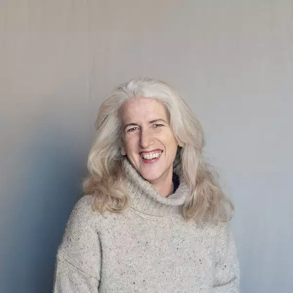 Headshot of Sue Buckmaster smiling on a grey background