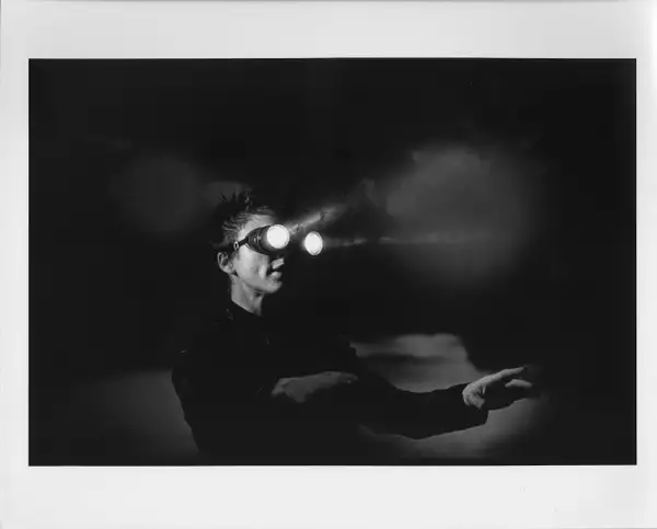 Black and white still from Laurie Anderson's United States Parts 1–4, showing Laurie wearing goggles with lights on