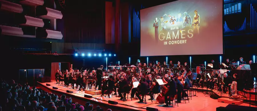 An orchestra on stage in front of a large screen which reads Bafta Games in Concert