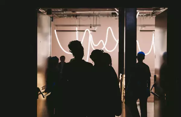 The outlines of people walking into the dark Warehouse – with bright lights in the stairway