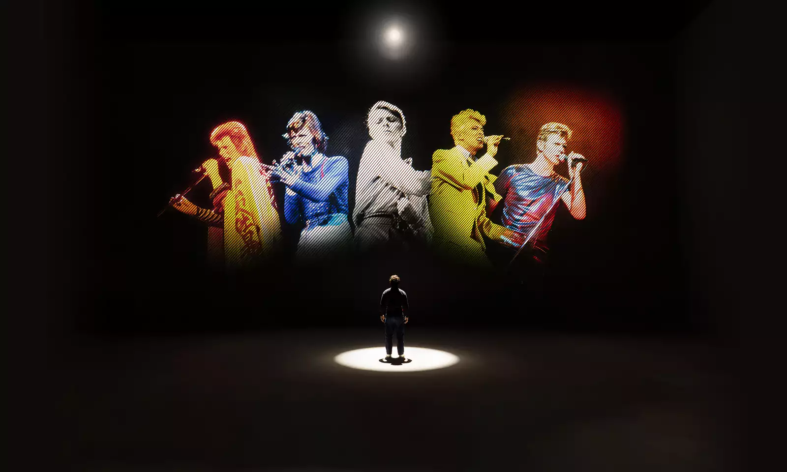 A person looking at five versions of David Bowie singing on a large screen