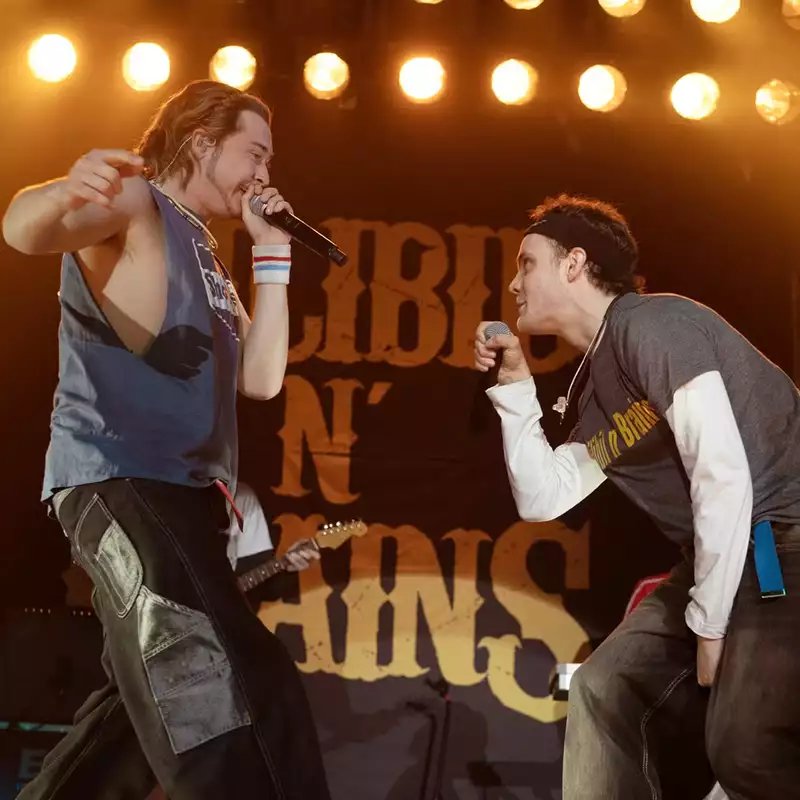 A still from California Schemin' showing two men on stage singing into a microphone