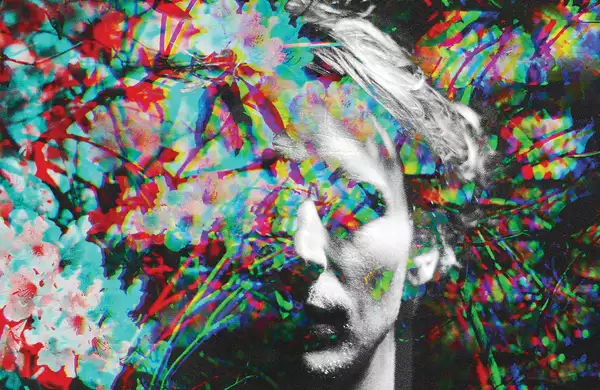 Ben Howard standing amid of a bush of flowers