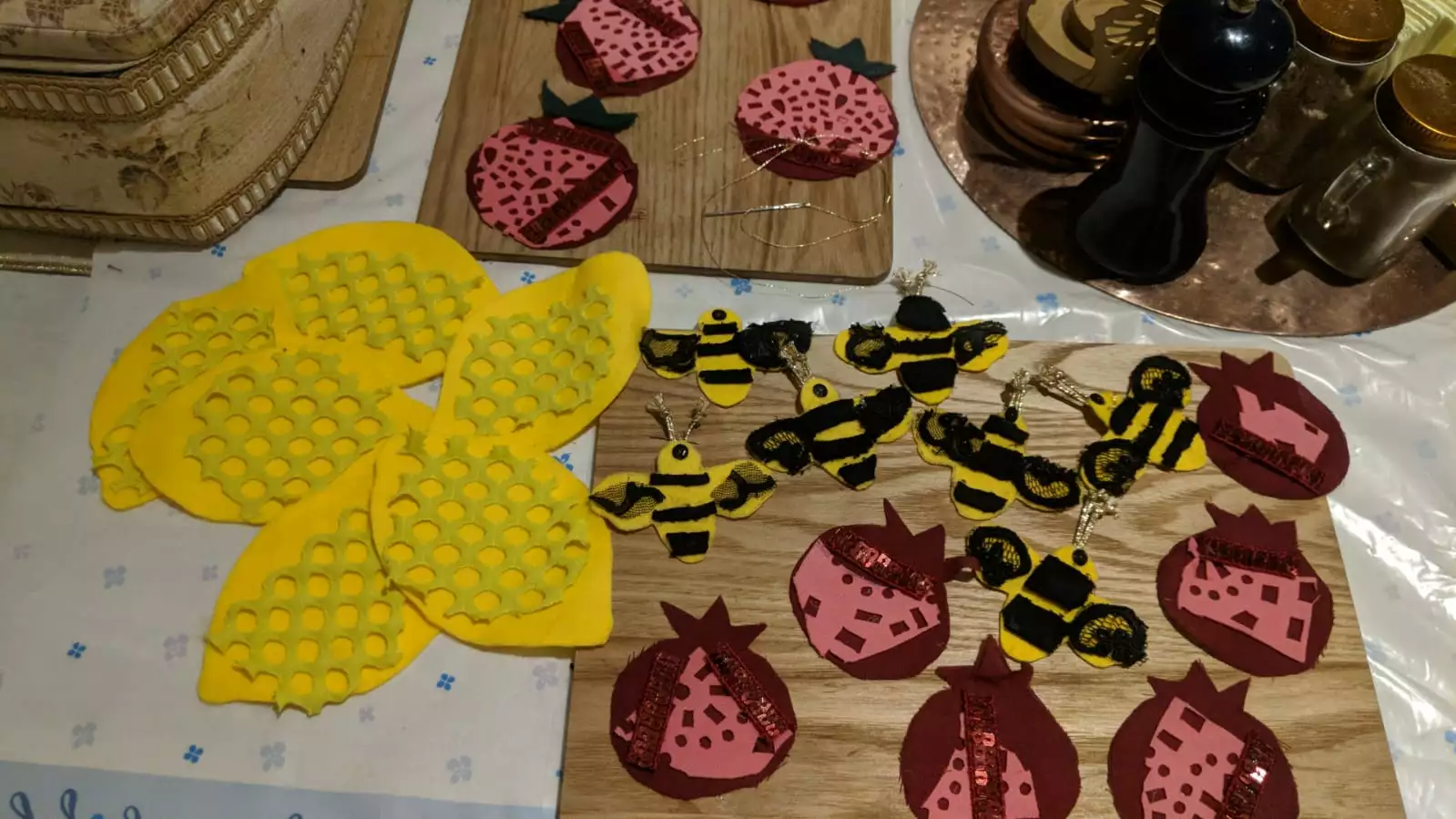 Fabric collages of lemons, bees and pomegranates laid out on a table.