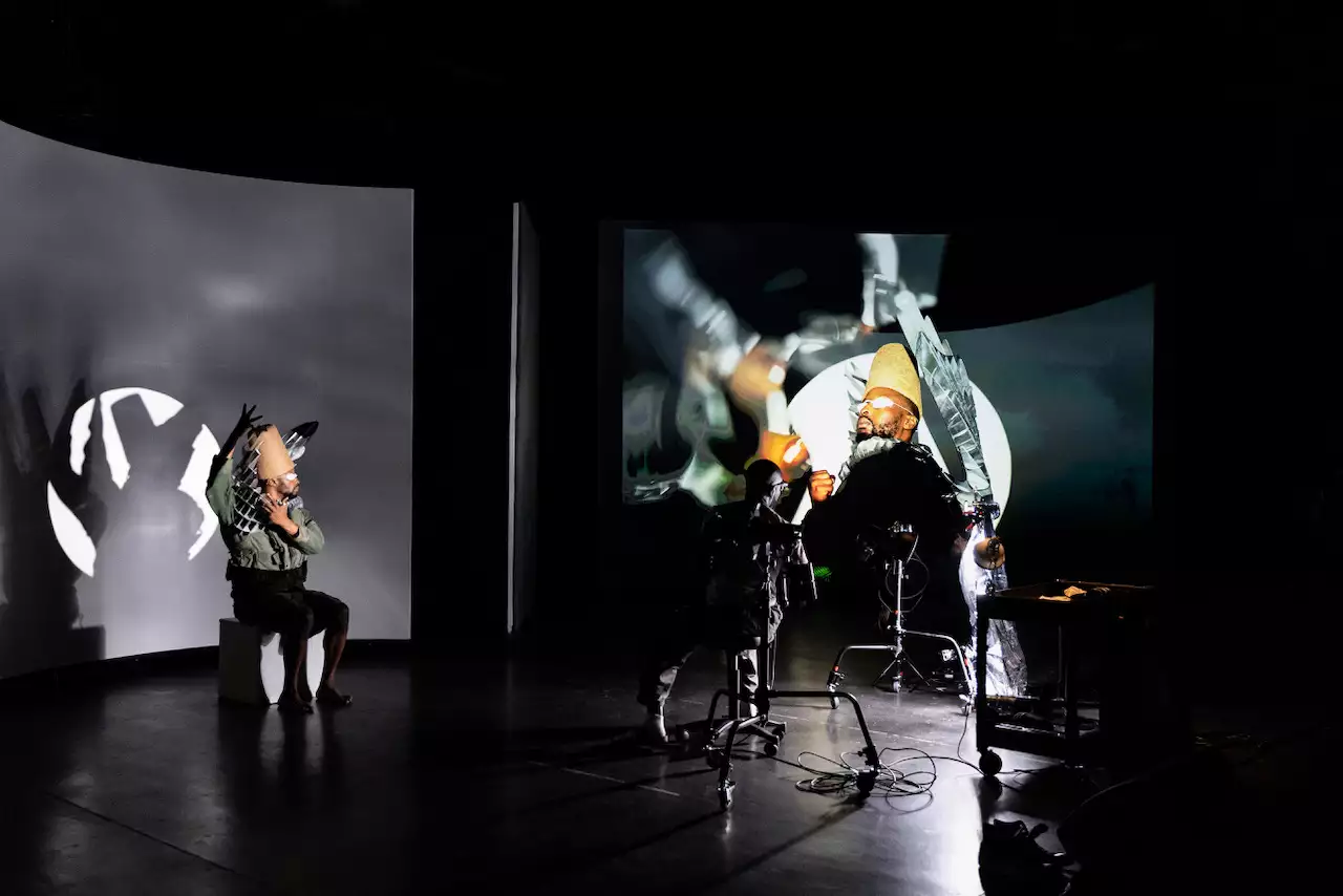 Benji Reid on stage looking at a photograph he has just taken