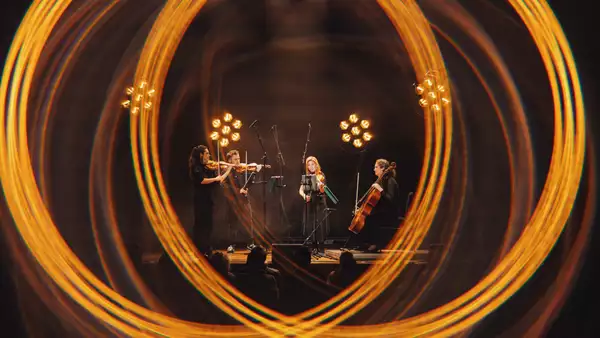 Four members of Manchester Collective perform on stage surrounded by blurred lighting