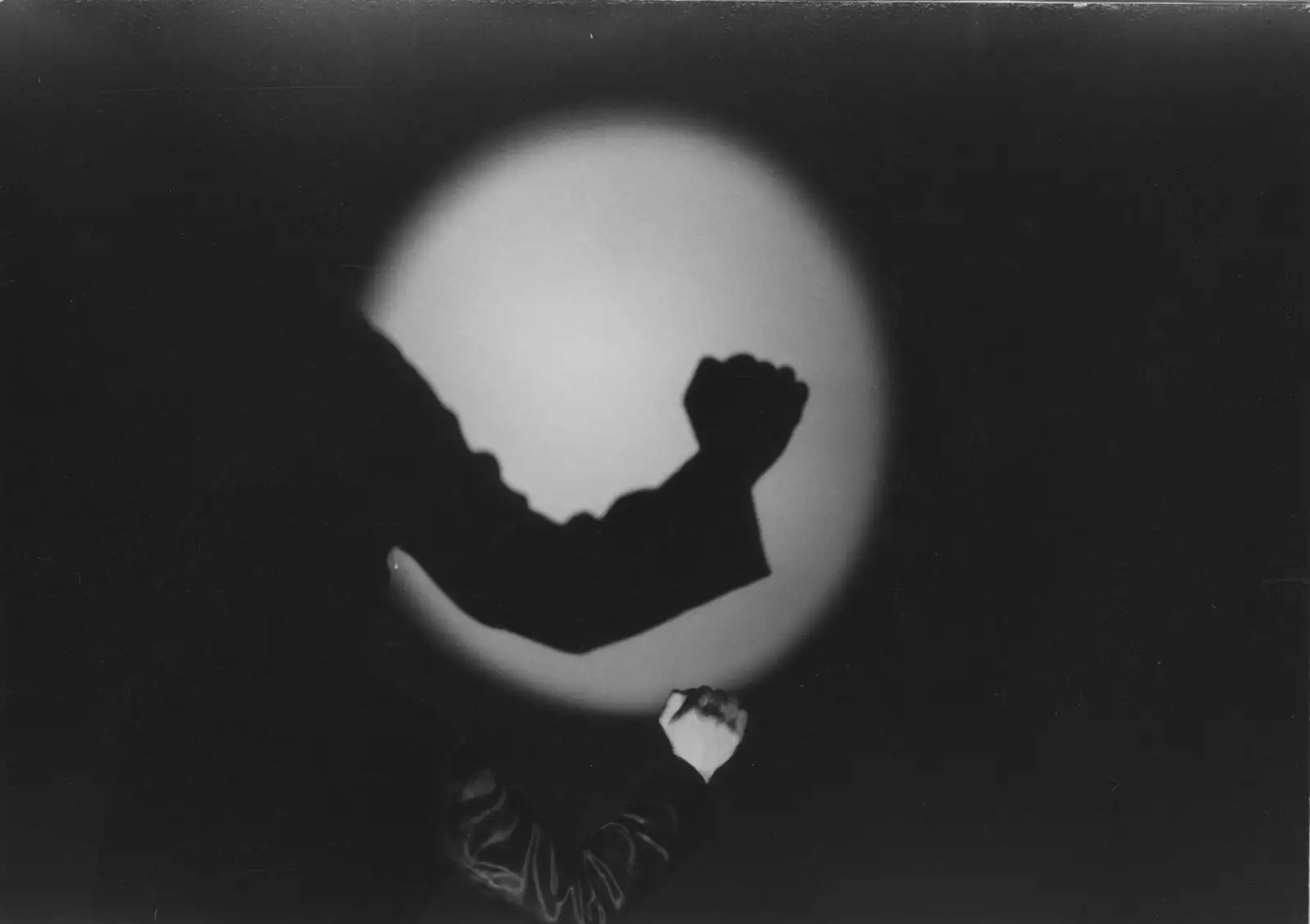 Black and white still from Laurie Anderson's United States Parts 1–4, showing the silhouette of an arm in front of a projector