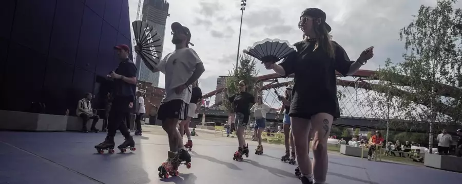 People roller skating with fans outside Aviva Studios in the sunshine
