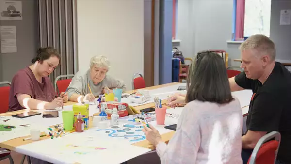 Photo of four people sat at a table painting
