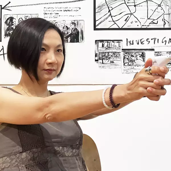 Clara Cheung pointing a pretend gun made out of paper