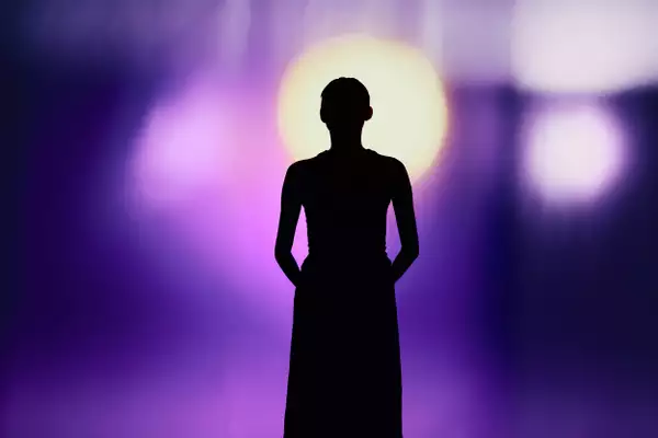 A silhouette of a person against a background with bright purple light