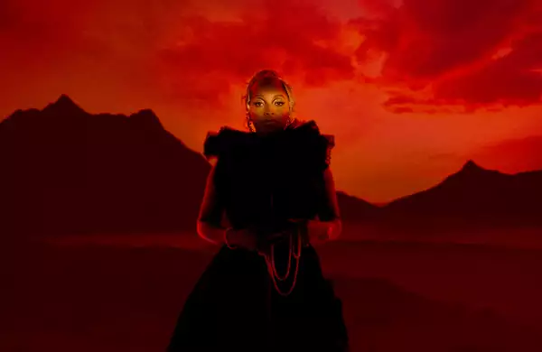 Photo of Nubya Garcia standing in front of a red sky with a backdrop of a mountain ridge