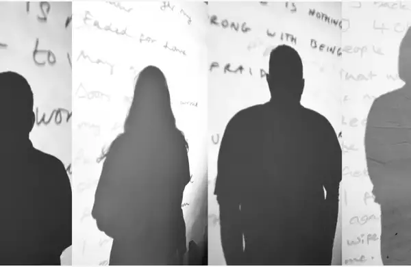 Silhouettes of four people cast on a wall with handwritten text in the background.