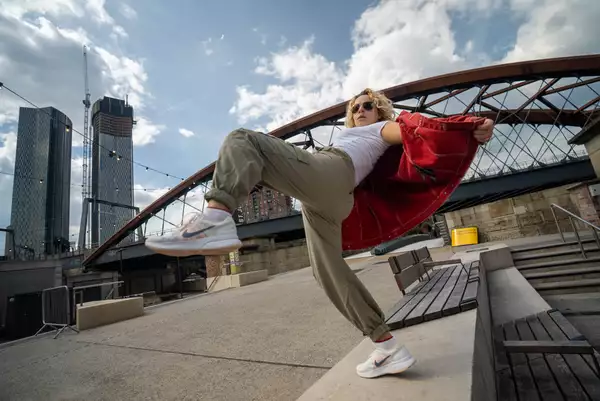A person posing on a bench outside Aviva Studios wearing sunglasses