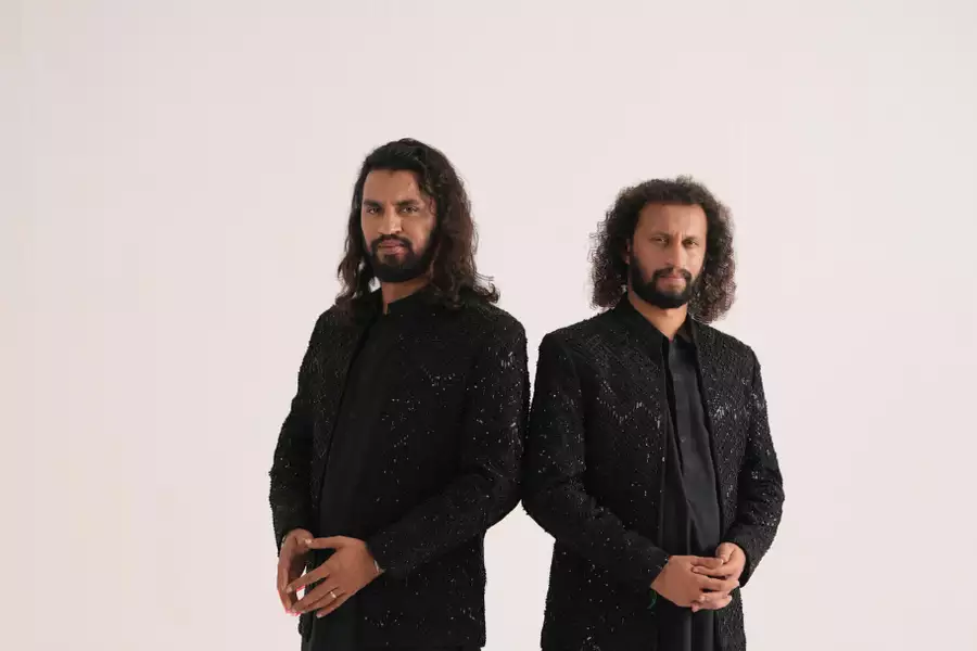 Two members of Zain Zohaib wearing black jewelled outfits on a white background