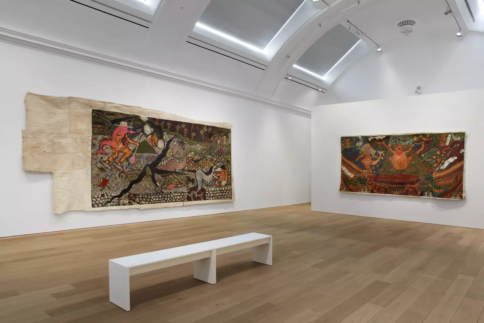 A photo of a brightly lit gallery with white walls and large paintings