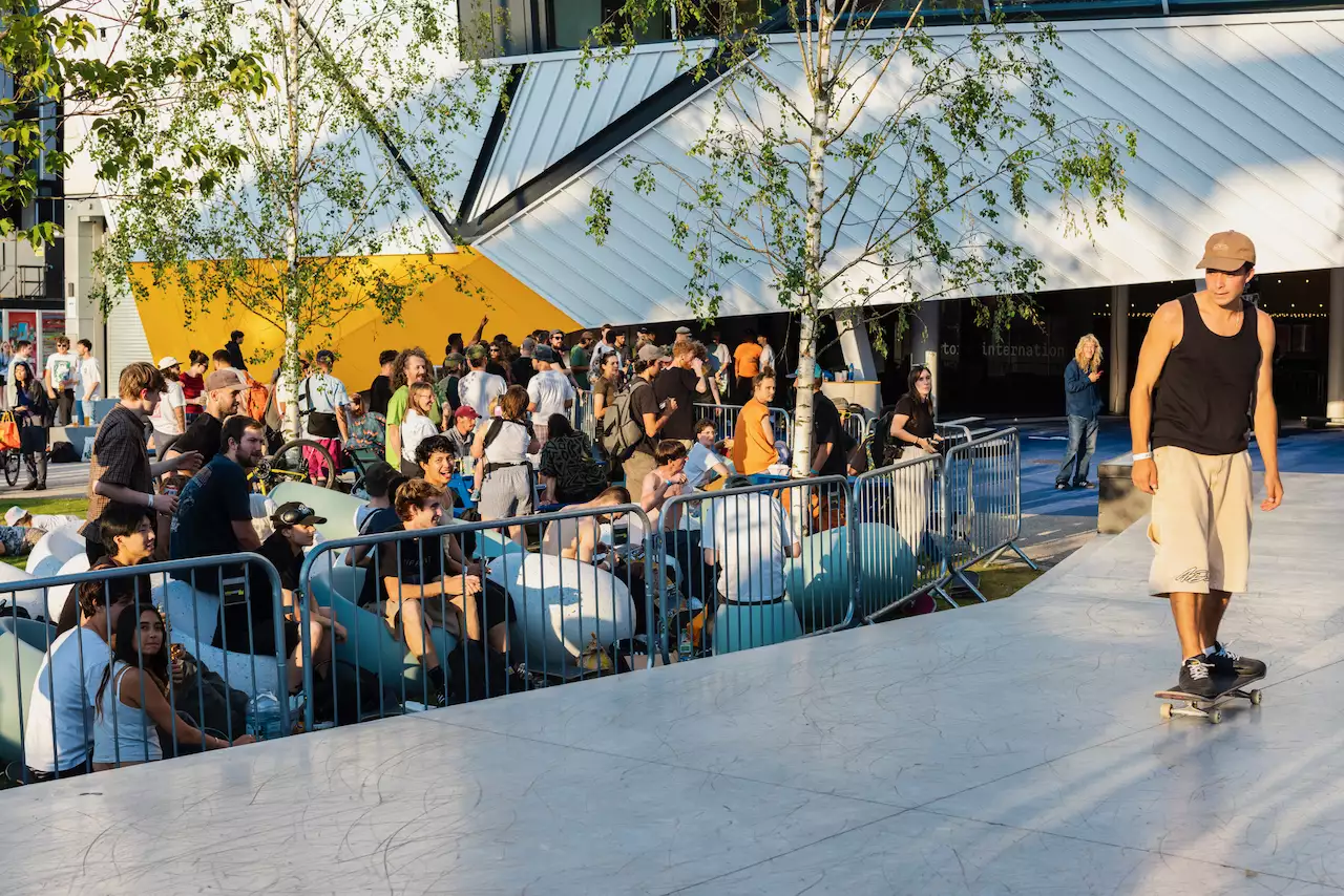 A skateboarder on the main ramp outside Aviva Studios during Build Manchester. There is a crowd of people watching.
