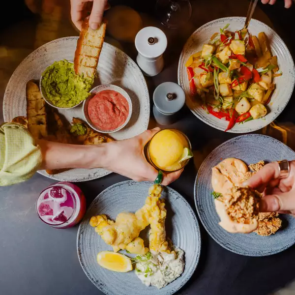 Three people pick small plates with Thai street food