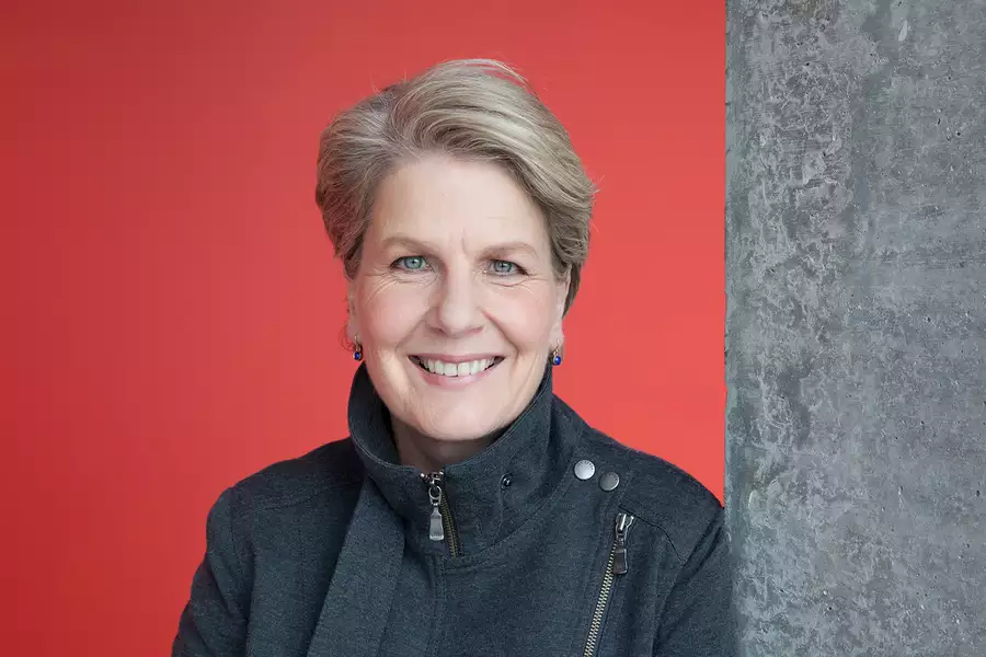 Sandi Toksvig smiling in front of a red wall