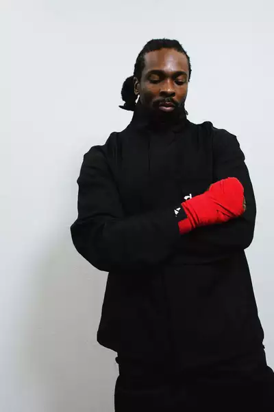Daniel Amadi wearing all black clothing and a red glove