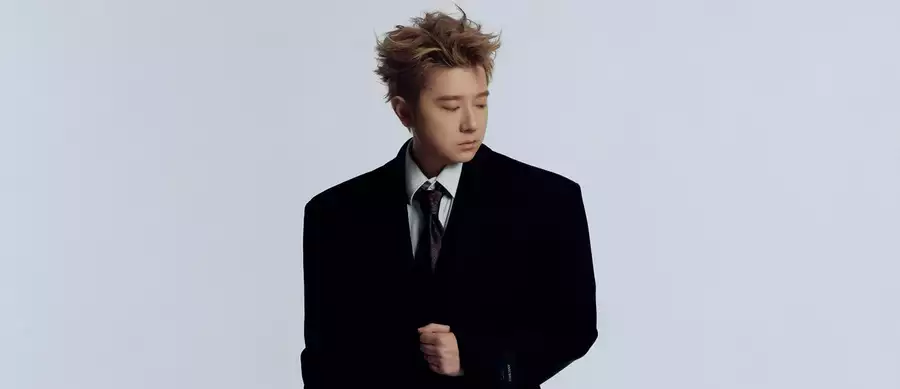 Wang Yitai wearing a black suit, looking to the right. On a white background.