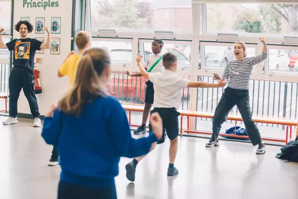 A school session with an adult female in an expressive pose front of schoolchildren