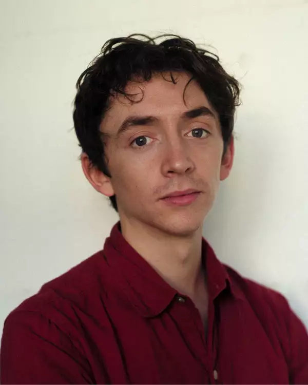 Headshot of Samuel Blenkin wearing a red shirt