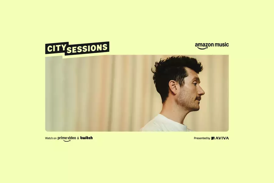 Dan Smith from Bastille in front of a softly lit beige curtain background. There is a yellow border with Amazon Music City Sessions Presented by Aviva in black text