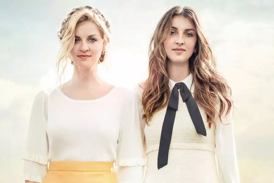 Two members of Ward Thomas stood against a pale sky background smiling