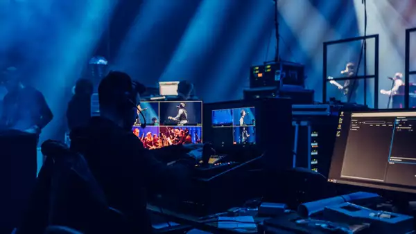 A technician working backstage at the Johnny Marr performance, managing live concert footage on computers.