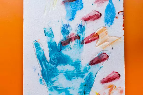 An impression of a handprint in blue paint on white card