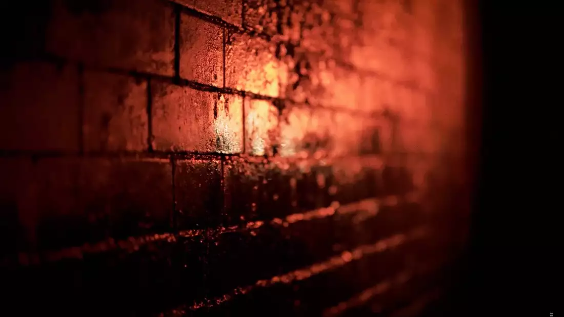 A still photograph showing a brick wall in red lighting